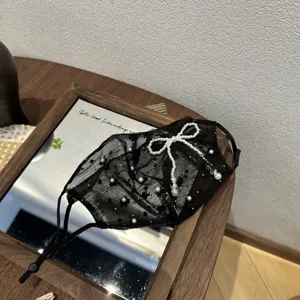 Detailed close-up of the black lace mesh face mask adorned with elegant pearls and bow.