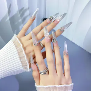 Detail view of handmade ultra long pointy press on nails featuring white butterflies and rhinestones.