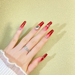 Detailed close-up view of luxury wine red gradient press-on nails with sparkling rhinestones.