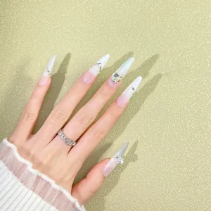 Detail view of white silver cat eye press on nails, long stiletto handmade nails with stones.