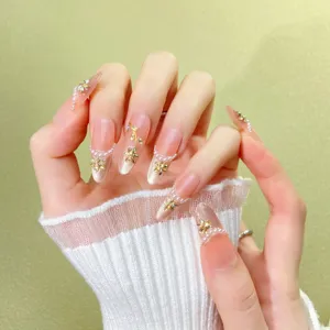 Stunning nude pink gradient press-on nails featuring delicate gold flowers, pearls, and rhinestones.