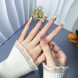Handcrafted press-on nails with nude gold cat-eye gradient and sparkling rhinestone details.