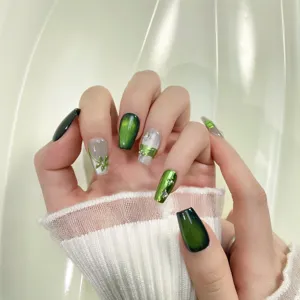 Detail shot of handmade green cat eye press on nails featuring elegant floral art and rhinestones.