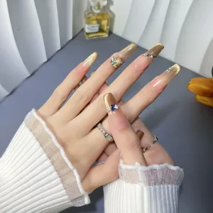 Uñas postizas largas hechas a mano con degradado nude dorado y diamantes de imitación brillantes.
