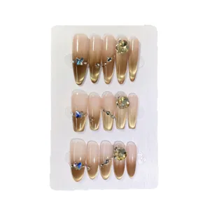 Uñas postizas hechas a mano con lujoso diseño degradado nude dorado cat-eye y gemas de cristal.