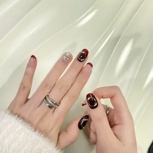 Gros plan détaillé de faux ongles bordeaux exquis avec des strass et un effet cat-eye.