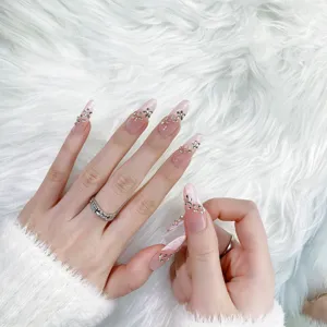 Close-up detail of handmade nude long press-on nails with delicate rhinestone flower art.