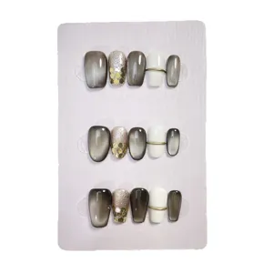 Uñas postizas hechas a mano con degradado negro y blanco y diseño de hoja de oro vista principal.