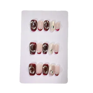 Faux ongles français bordeaux faits main avec strass délicats, design court et chic.