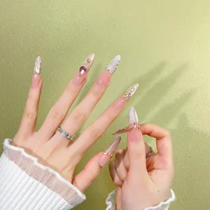 Gros plan d'ongles artificiels longs faits main avec texture coquillage et strass brillants.