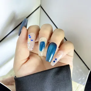 Gros plan des détails des faux ongles faits à la main avec dégradé œil-de-chat bleu et paillettes.