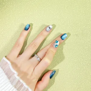 Primer plano de uñas postizas cat-eye azules con lazo elegante y brillantes azules.