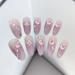 Detalle de uñas postizas hechas a mano con corazón de cristal rosa, estilo dulce y exquisito.