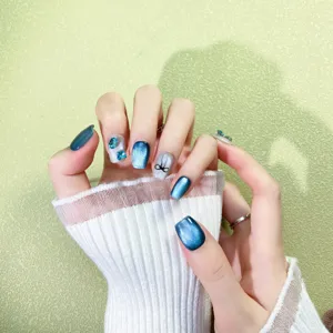 Uñas postizas de ojo de gato degradado azul con pedrería y lazos para un estilo veraniego.