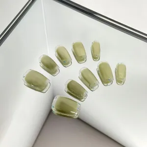 Avocado green press-on nails with cat-eye effect and glitter edge design, detail shot.