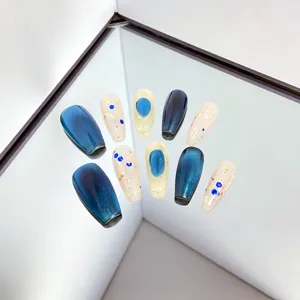 Vue détaillée de faux ongles faits main avec effet cat-eye bleu et dégradé pailleté.