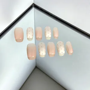 Detail shot of short press-on nails featuring a cute pink gradient and polka dot design.