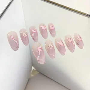 Uñas postizas hechas a mano con corazones de cristal rosa brillante y pedrería elegante.