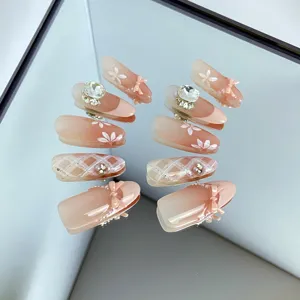Détail faux ongles nude, design d'ongles art brillant avec nœud fait main et strass élégants