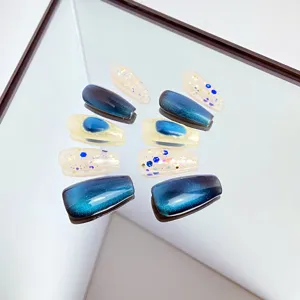 Faux ongles faits à la main avec dégradé bleu effet œil-de-chat et paillettes scintillantes.