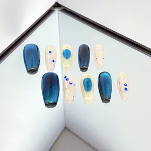 Faux ongles faits main avec dégradé œil de chat bleu, paillettes et design cristal 3D.