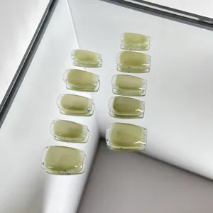 Avocado green press-on nails with cat eye and glitter edge, stylish false nail tips detail view.