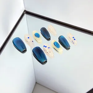 Détail de faux ongles faits main avec dégradé œil-de-chat bleu et finitions scintillantes.