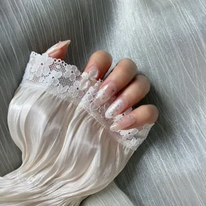 Close-up detail of blush pink press-on nails featuring 3D flower and starry rhinestone decor.
