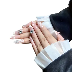 Faux ongles roses faits main ornés de nœuds élégants, strass brillants et motifs floraux.