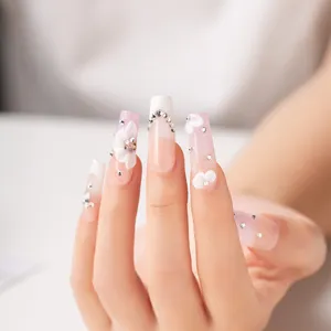 Uñas postizas hechas a mano con degradado rosa y blanco, flores y pedrería elegante.