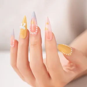 Uñas postizas stiletto largas con degradado rosa y amarillo, perles elegantes y lindo lazo.