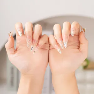 Faux ongles amande longue en dégradé nude, bouts français blancs et strass en cœur cristal.
