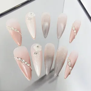 Close-up detail of gradient press-on nails featuring exquisite rhinestones and floral design.