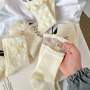 Close-up of sweet white Lolita JK mid-calf socks featuring delicate lace ruffles and bows.