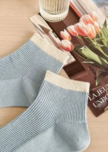 Close-up detail of light blue ribbed ankle socks with beige contrast cuff. Soft cotton fabric.