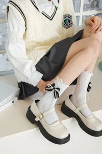 Close up of cute white lace mid-calf socks featuring sweet black bow and ruffle trim.