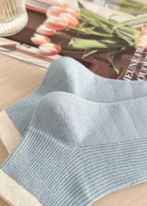 Close-up detail of light blue ribbed crew socks with contrast beige hem, soft cotton knit.