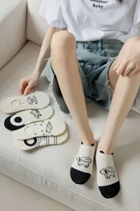 Detail shot of cute beige boat socks with black toe and playful dog graphic prints worn nicely.
