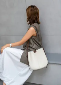 Minimalist leather bucket shoulder bag in cream white with brown strap for women daily commute.