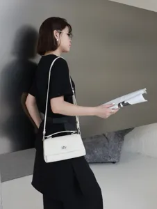 Vue détaillée de l'élégant sac bandoulière en cuir blanc avec serrure métallique.