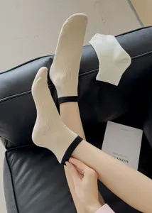 Detailed shot of beige mid-tube socks featuring black ribbed cuffs and vertical knit texture.
