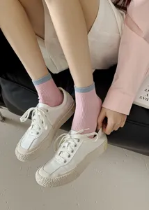 Close-up detail of stylish women pink ribbed mid-tube socks paired with casual white sneakers.