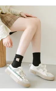 Cute bear embroidered black mid-tube socks for women, paired with casual white sneakers.