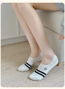 Close-up detail of white invisible boat socks with black stripes and cute smiley face embroidery.