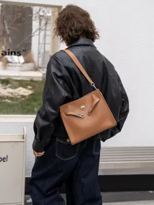 Detalle de bolso de hombro de cuero marrón, estilo vintage con cierre metálico.