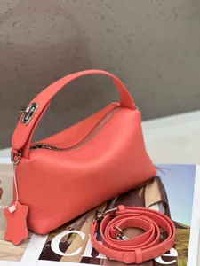 Close-up detail of coral pink genuine leather pillow handbag, showing soft texture and hardware.