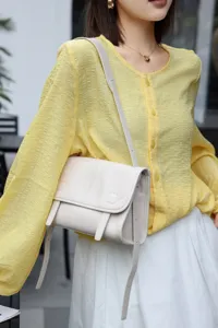 Close-up detail of genuine leather crossbody messenger bag worn by model showing texture.