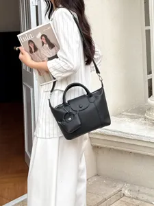 Detailed lifestyle view of black genuine leather tote shoulder bag with mini pouch prop.