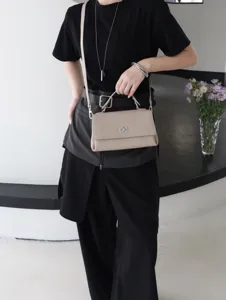 Vue détaillée d'un élégant sac à main en cuir beige avec fermoir en métal argenté et bandoulière.