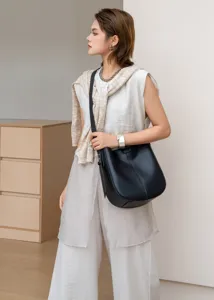 Detailed view of the black leather bucket shoulder bag worn by model, minimalist style.